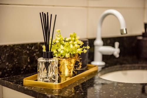 a kitchen counter with a sink and a vase with flowers at Apartamento com Café no 1º Dia, Kit Fondue e Aquecedor no Quarto a 300m da Praia para Casais in Imbituba