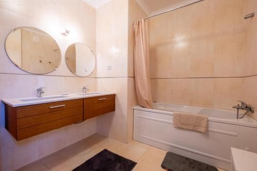 a bathroom with a sink and a tub and a mirror at Praça da Cultura Residence in Buarcos
