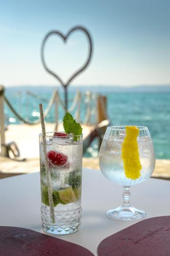 a glass of water and a drink with fruit on a table at Hotel Catullo in Sirmione