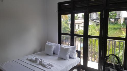 a bedroom with a bed with white pillows and a window at Shalom View Homestay in Kandy