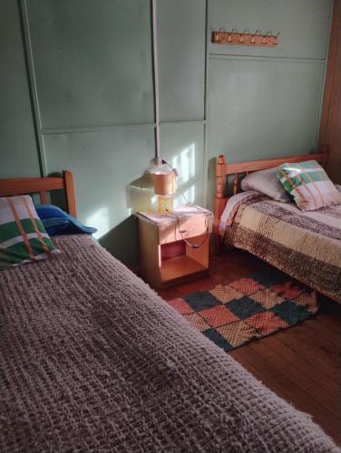 a bedroom with two beds and a lamp on a table at Hospedaje Chumaihuen in Quellón
