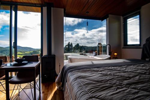 a bedroom with a bed and a bathroom with a tub at Studio Sunrise - Luxo, Romance e Natureza in Rancho Queimado