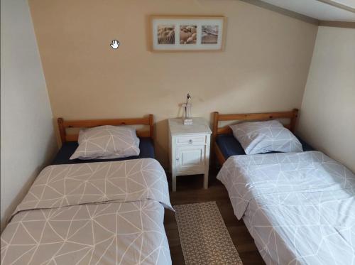 a bedroom with two beds and a night stand with a nightstandozy at Zeevibes - Sunparks - Waterpret - gratis fietsen! in Oostduinkerke
