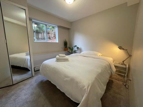 a bedroom with a large white bed and a mirror at 2-Bedroom Suite in North Vancouver