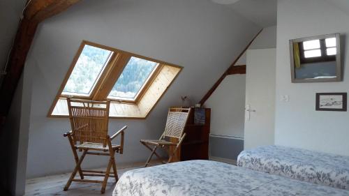 um quarto com 2 cadeiras, uma cama e uma janela em La Chouette à l'heure du Pinson em Saint-Pierre-dʼEntremont