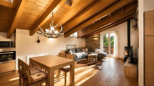 a dining room and living room with a wooden ceiling at Chalet la Segheria in Temù