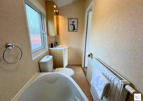 a bathroom with a tub and a toilet and a window at Rupert's Lodge in West Down