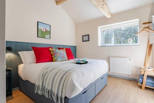a bedroom with a large bed with red pillows at The Cove at Thorpewood in Thorpe Market