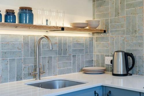 a kitchen with a sink and a counter with dishes at The Cove at Thorpewood in Thorpe Market