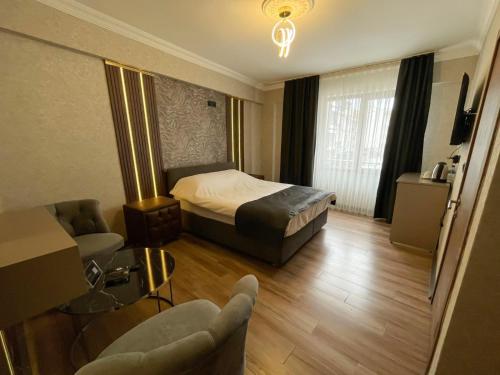 a hotel room with a bed and a couch and chairs at Kütahya Şehir Otel in Kütahya