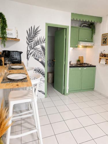 a kitchen with green cabinets and a table and chairs at Studio cosy à Bas-du-Fort in Le Gosier