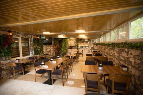 a restaurant with wooden tables and chairs and a brick wall at Kütahya Şehir Otel in Kütahya