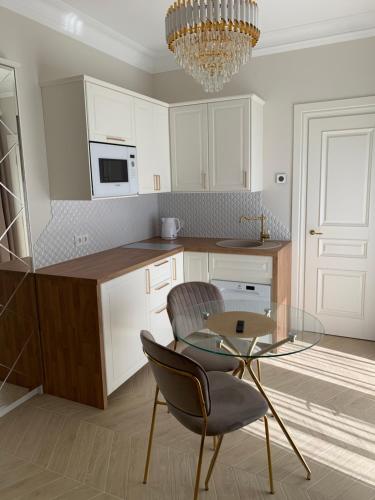 a kitchen with a glass table and a chandelier at Vaineikio 8 in Palanga