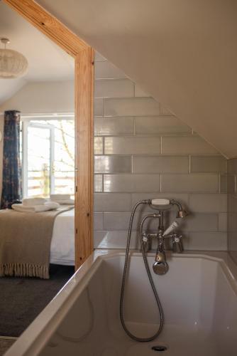 a bath tub with a shower in a room with a bed at Saltspring Lodge in Oban