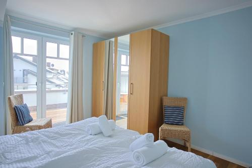 a bedroom with a white bed and two chairs at Strandvilla Börgerende in Börgerende-Rethwisch
