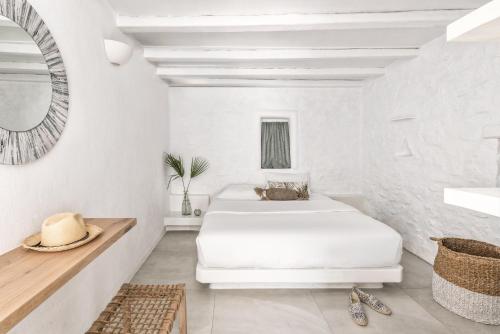 a white bedroom with two beds and a mirror at A Hotel Mykonos in Mikonos