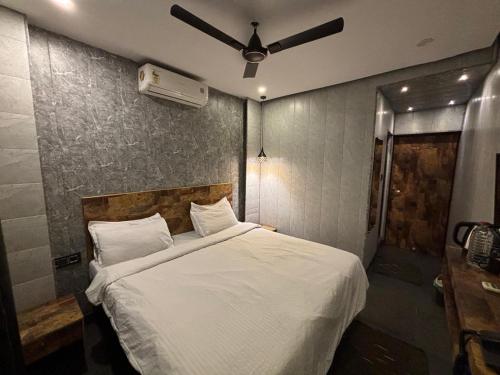 a bedroom with a white bed with a ceiling fan at Aariv Inn BAGA BEACH in Baga