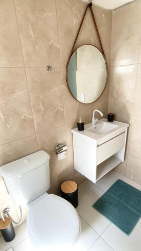 a bathroom with a toilet and a sink and a mirror at Casa Ubatuba in Ubatuba