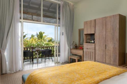 a bedroom with a bed and a table and a balcony at Ayuda Sanctuary Boutique Negombo in Negombo