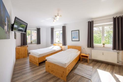 a bedroom with two beds and two windows at Apartment-Haus Gundelfinger in Gräfenberg