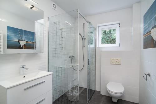 a white bathroom with a shower and a toilet at Willa Di Mare in Karwia