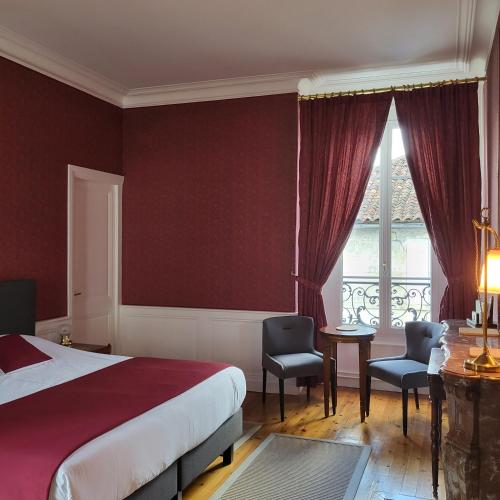 a bedroom with a bed and a desk and a window at Logis des Tourelles in Cognac