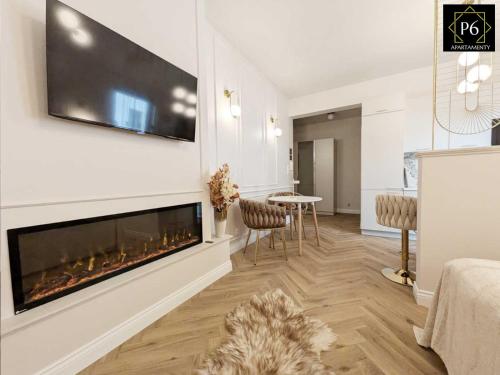a living room with a fireplace and a table and chairs at P6 Apartament Kaszmirowy in Pisz