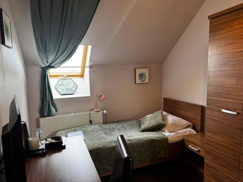 a small bedroom with a bed and a window at Garden Zajazd in Rzeszów
