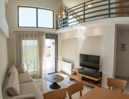 a living room with a couch and a tv at Evi Seaside Suites in Kanali
