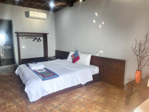a bedroom with a bed with white sheets and a mirror at Villa Thẩm mã in Dồng Văn