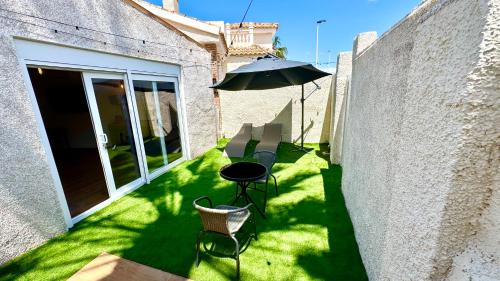 a patio with a table and chairs and an umbrella at 16 Casita con Jacuzzi privado in Gran Alacant