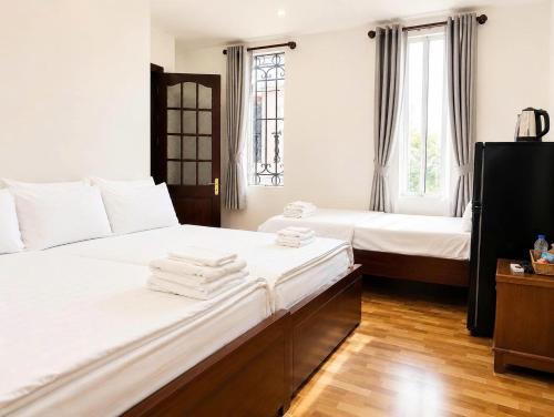 two beds in a room with two windows at KS Phương Danh in Quy Nhon