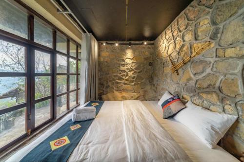 a bed in a room with a stone wall at Villa Thẩm mã in Dồng Văn