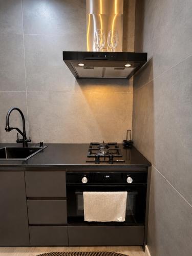 a kitchen with a stove and a sink at Hostly, New Boulevard Prime Stay in Batumi