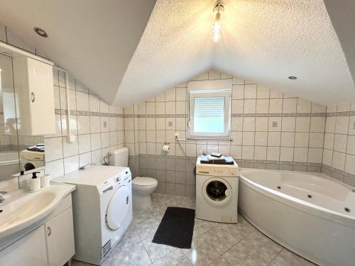 a bathroom with a tub and a sink and a washing machine at Kovač Home in Posušje