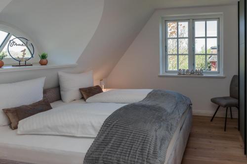 a white bedroom with a bed and a window at Friesenfrühling in Borgsum