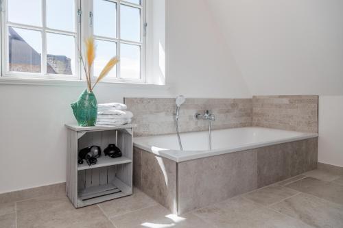 ein Badezimmer mit Badewanne und einer Vase mit einer Pflanze in der Unterkunft Sommergeest in Borgsum