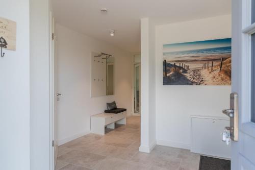 a hallway with white walls and a desk with a laptop at Reetruhe in Borgsum