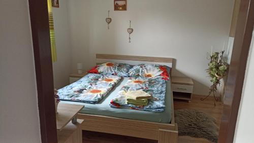 a bed with floral sheets and a backpack on it at J&K Štrba in Poprad