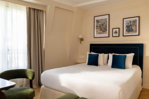 a hotel room with a large bed with blue pillows at Hotel Du Flaneur in Paris