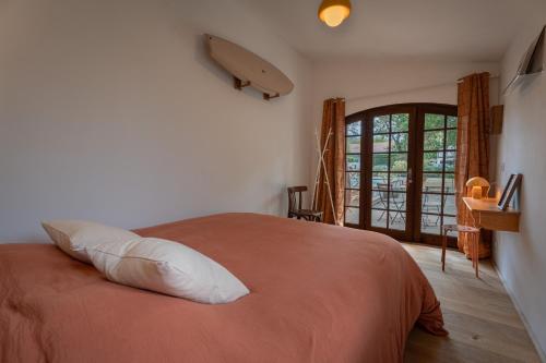 a bedroom with a bed with an orange blanket at Brume Surf House in Messanges