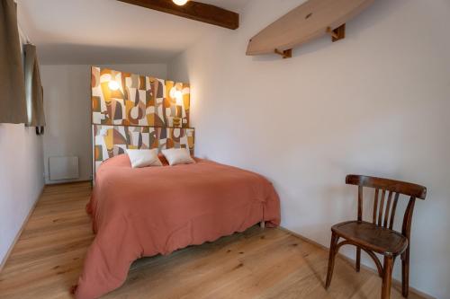 a bedroom with a bed and a wooden chair at Brume Surf House in Messanges