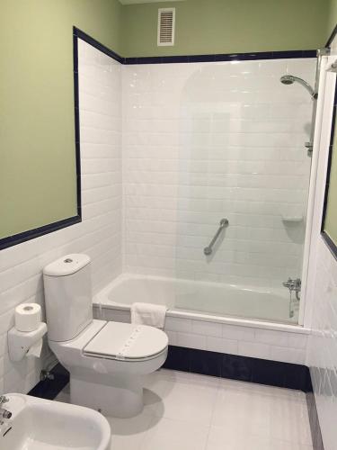 a white bathroom with a toilet and a bath tub at Hotel La Balastrera in Ribadeo