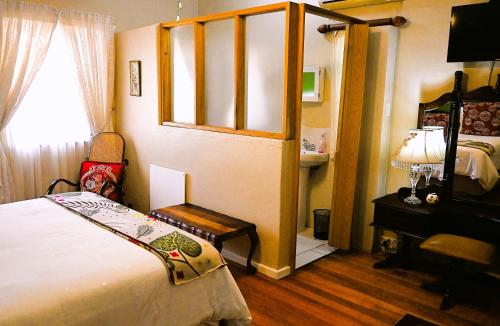 a bedroom with a bed and a chair and a window at Beau & I in Graaff-Reinet