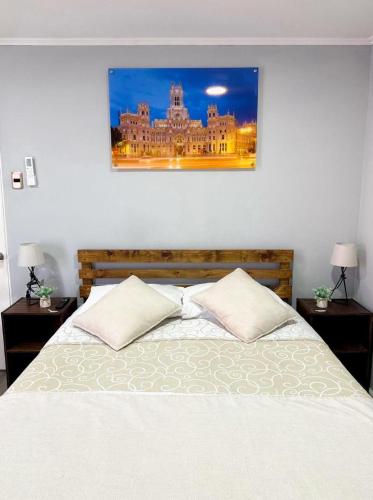 a bedroom with a bed with two pillows and a picture on the wall at Hostal Madrid in Talca