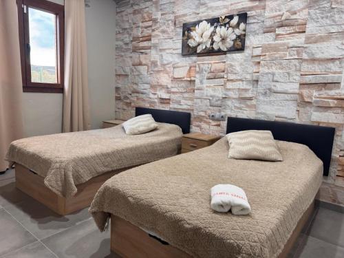 two beds in a room with a stone wall at Complejo Rural Santa Emma in Herencia