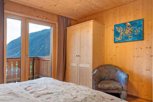 a bedroom with a bed and a chair and a window at Felderhof in Villa Ottone