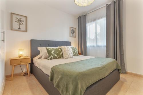 a bedroom with a bed with a nightstand and a window at Casa Oasis in Corralejo