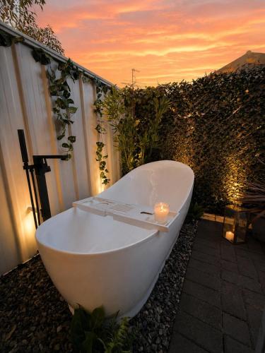 a white bath tub sitting on the ground with a candle at Glamorous Getaway in Mandurah