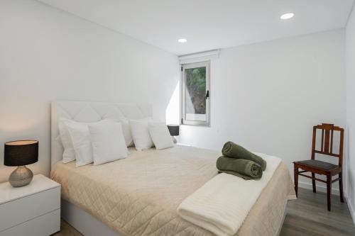 a white bedroom with a large bed and a chair at OurMadeira - Terrace Sea Apartments in Ribeira Brava